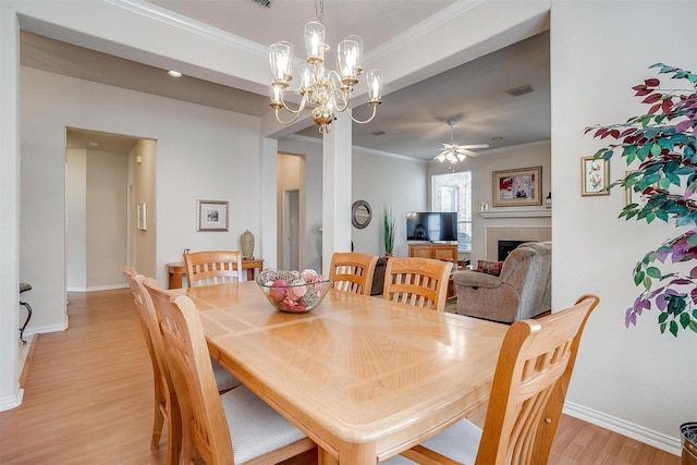 dining space featuring ornamental molding, a tile fireplace, visible vents, and light wood-style floors