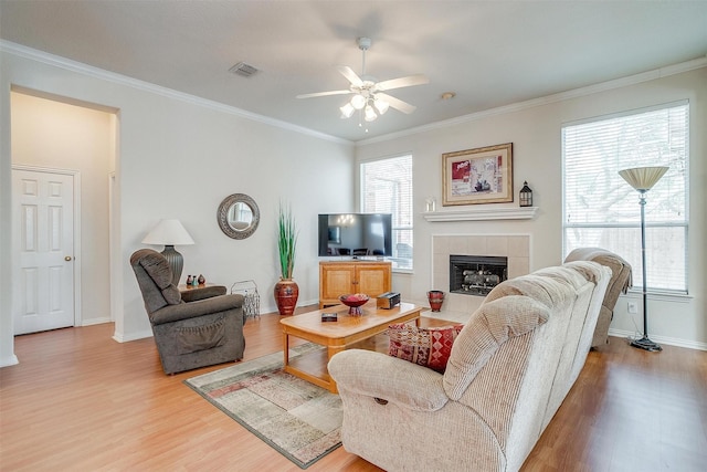 living area with light wood-style floors, a wealth of natural light, visible vents, and crown molding