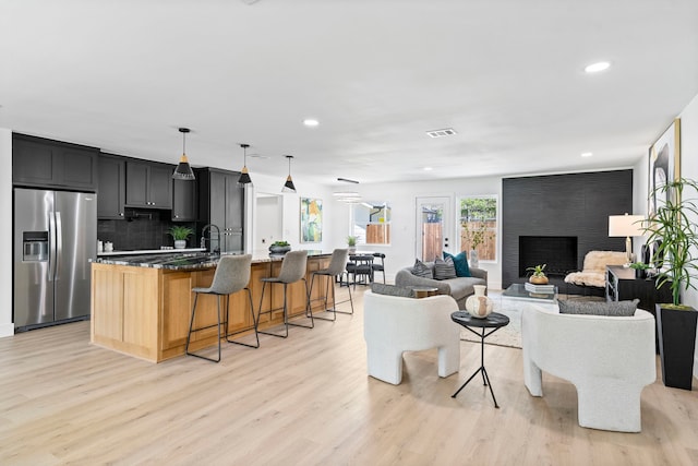 living area with recessed lighting, visible vents, a fireplace, and light wood finished floors