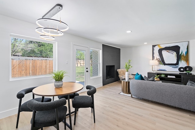 dining area featuring a fireplace, recessed lighting, an inviting chandelier, light wood-style floors, and baseboards