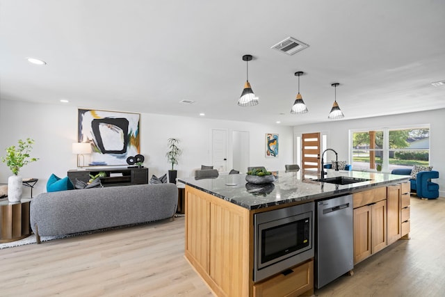 kitchen featuring appliances with stainless steel finishes, visible vents, a sink, and light wood finished floors