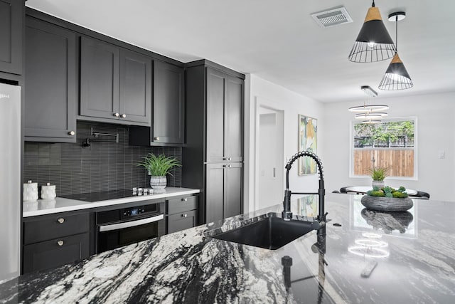 kitchen with black electric stovetop, visible vents, decorative backsplash, wall oven, and a sink