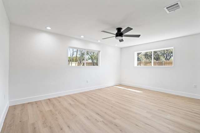 spare room with light wood-style floors, a wealth of natural light, visible vents, and baseboards