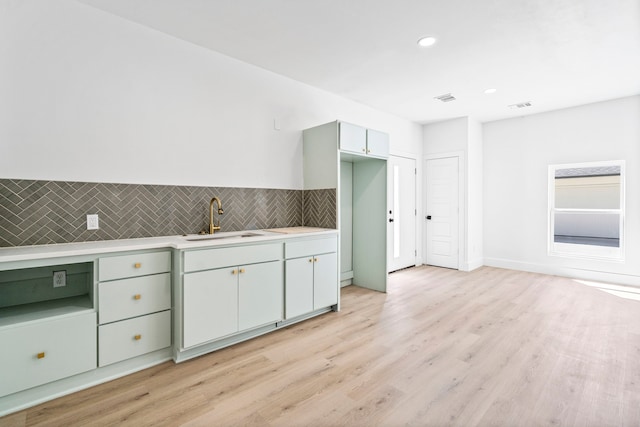 kitchen with light wood-style flooring, light countertops, a sink, and visible vents