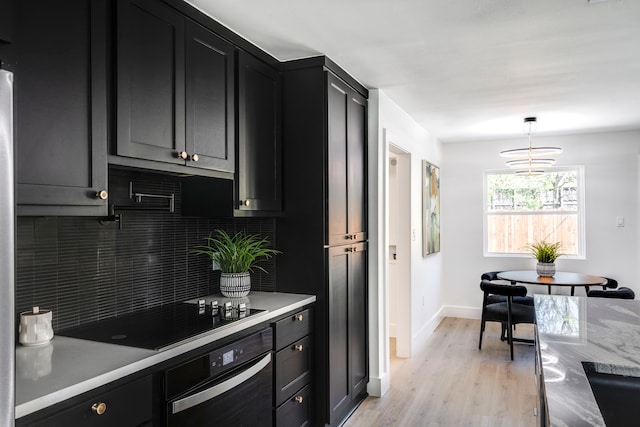 kitchen with baseboards, decorative backsplash, dark cabinets, light wood-type flooring, and black appliances