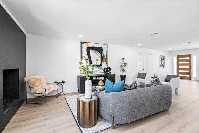 living area featuring a large fireplace, visible vents, wood finished floors, and recessed lighting