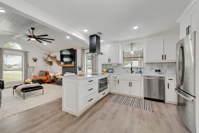 kitchen with appliances with stainless steel finishes, open floor plan, island exhaust hood, and a peninsula