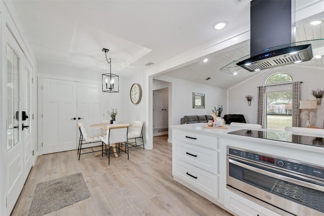 kitchen with vaulted ceiling with beams, island exhaust hood, light wood-style flooring, white cabinetry, and stainless steel oven