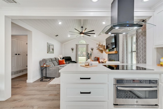 kitchen with island exhaust hood, black electric stovetop, lofted ceiling, white cabinets, and oven