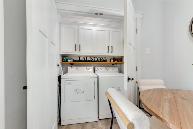 laundry room featuring cabinet space, washer and clothes dryer, and light wood finished floors