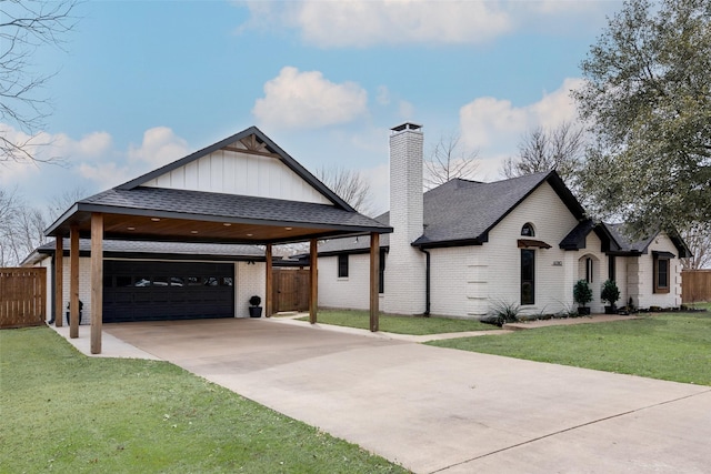 view of front of home with brick siding, a chimney, concrete driveway, a front yard, and fence