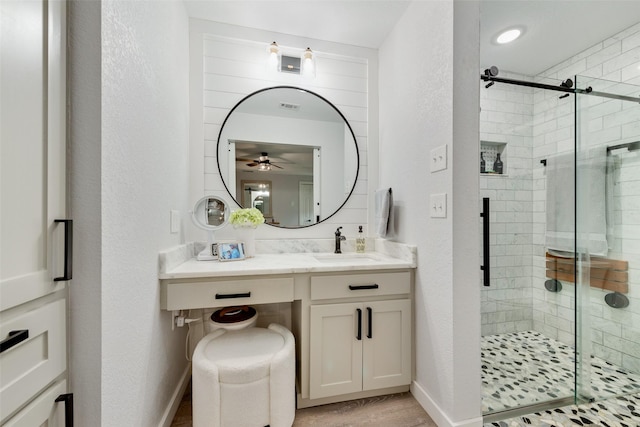 full bathroom featuring a textured wall, a stall shower, vanity, and baseboards