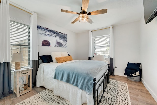 bedroom with ceiling fan, light wood-style flooring, and baseboards