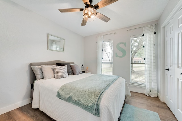 bedroom with a ceiling fan, baseboards, and wood finished floors