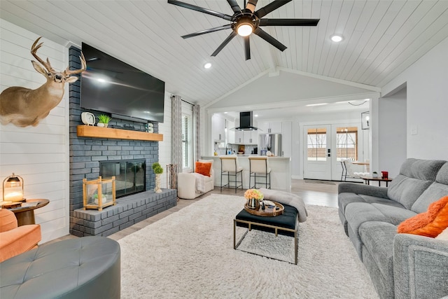 living area with lofted ceiling with beams, wood ceiling, french doors, light wood-style floors, and a fireplace