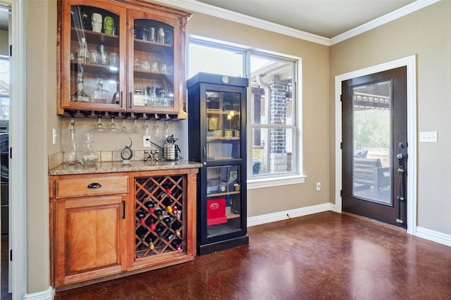 bar featuring concrete flooring, baseboards, backsplash, a bar, and crown molding