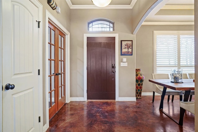 entryway with concrete flooring, arched walkways, baseboards, french doors, and crown molding