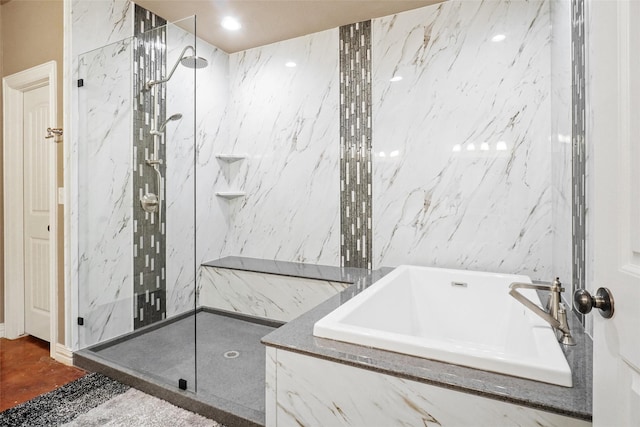 bathroom with a marble finish shower, a sink, a bath, and tile walls