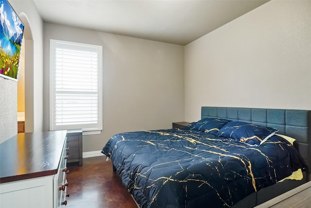 bedroom with concrete floors and baseboards