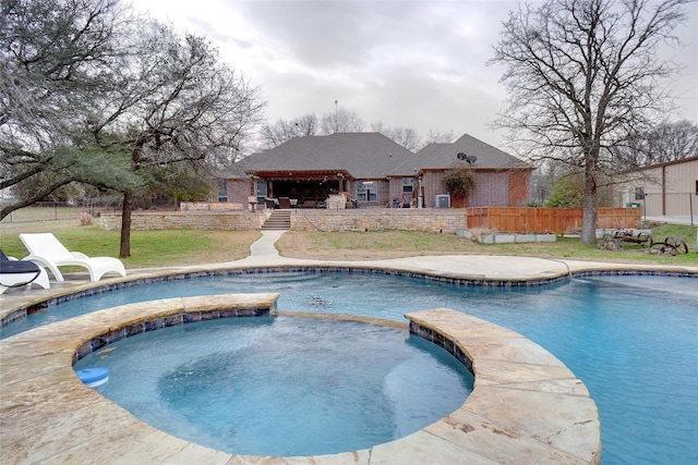 view of pool featuring a patio area, a pool with connected hot tub, fence, and a yard