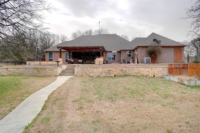 back of property with brick siding, a shingled roof, fence, a yard, and a patio area