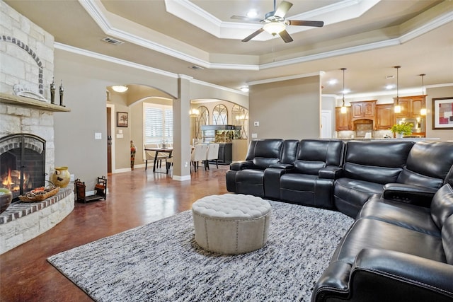 living room featuring a tray ceiling, visible vents, a fireplace, and arched walkways