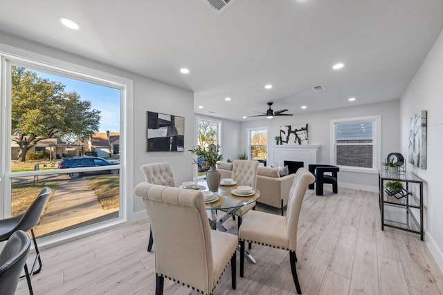 dining room with light wood finished floors, a fireplace, visible vents, and recessed lighting