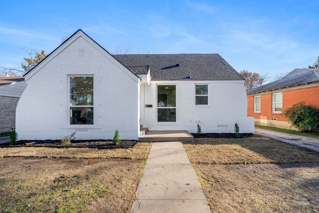 bungalow-style house with crawl space, a shingled roof, and brick siding