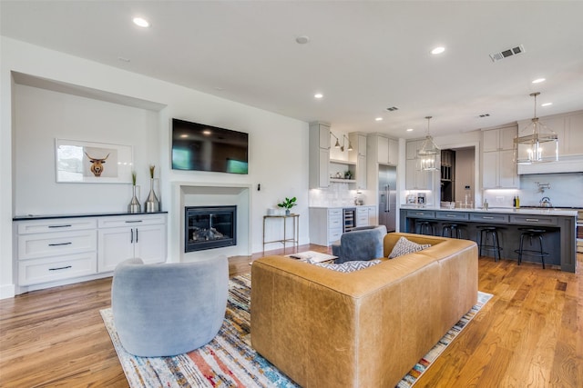 living area with light wood-type flooring, recessed lighting, and a glass covered fireplace