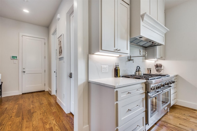 kitchen featuring light countertops, double oven range, premium range hood, and light wood finished floors