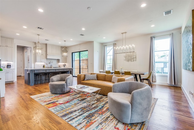 living area featuring a notable chandelier, wood finished floors, visible vents, and recessed lighting