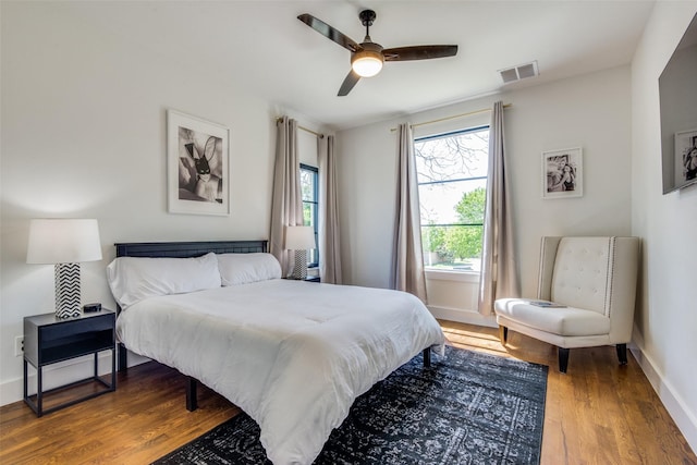 bedroom featuring visible vents, ceiling fan, baseboards, and wood finished floors