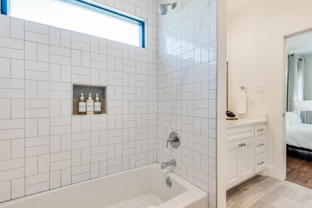 ensuite bathroom featuring vanity, wood finished floors, connected bathroom, and bathing tub / shower combination