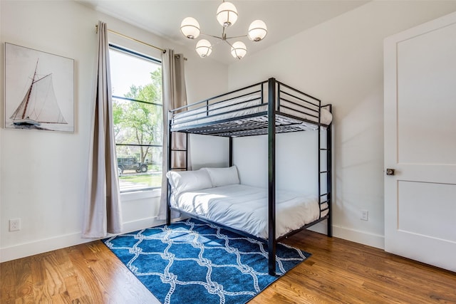 bedroom featuring a notable chandelier, baseboards, and wood finished floors