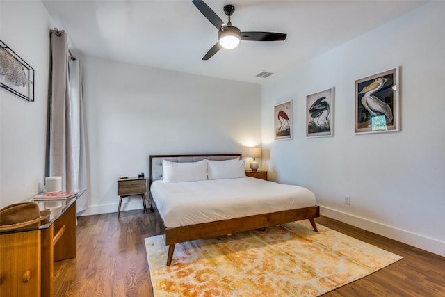 bedroom featuring dark wood-type flooring, a ceiling fan, visible vents, and baseboards