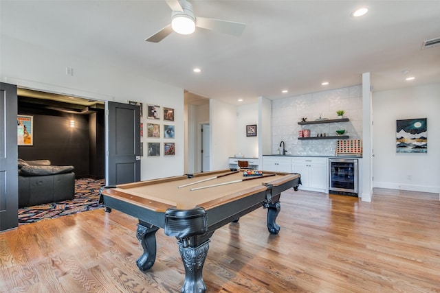 rec room with light wood-style flooring, wine cooler, indoor wet bar, and recessed lighting