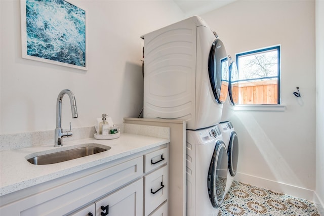 washroom featuring baseboards, a sink, and stacked washer / drying machine