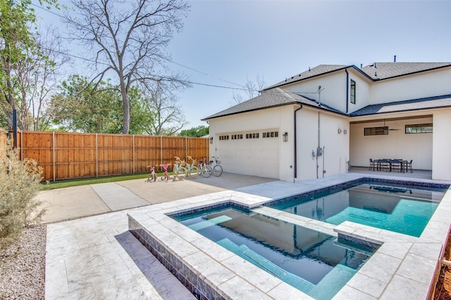 view of swimming pool with a patio, fence, and a pool with connected hot tub