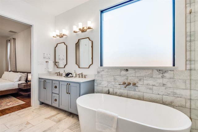 full bath featuring double vanity, a soaking tub, visible vents, ensuite bathroom, and a sink