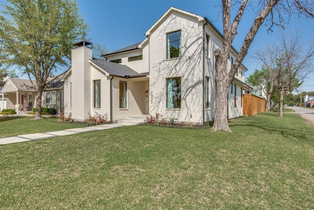 view of front of house featuring a front yard, a chimney, and brick siding