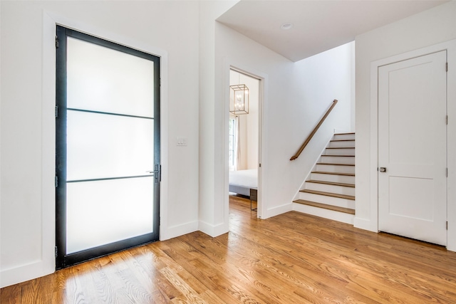 foyer entrance featuring stairs, baseboards, and light wood-style floors