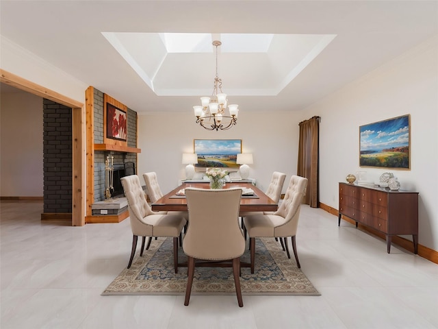 dining space featuring a chandelier, a tray ceiling, a brick fireplace, and baseboards