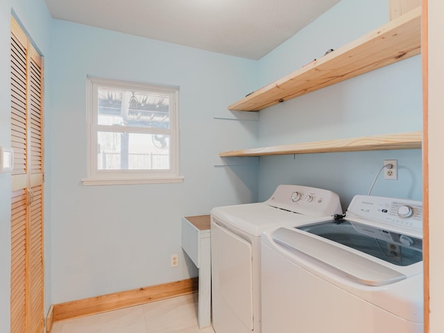 clothes washing area featuring independent washer and dryer, light tile patterned flooring, and baseboards