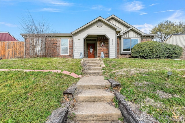 view of front of property featuring a front lawn, board and batten siding, fence, and brick siding