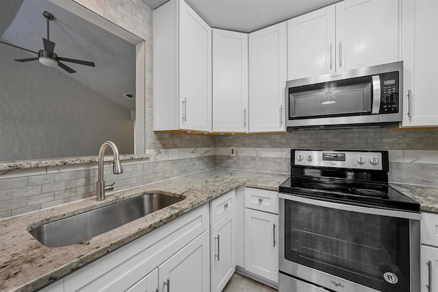 kitchen featuring appliances with stainless steel finishes, white cabinetry, a sink, and tasteful backsplash