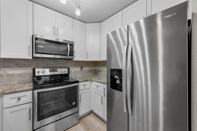 kitchen featuring stainless steel appliances, white cabinets, backsplash, and light wood finished floors