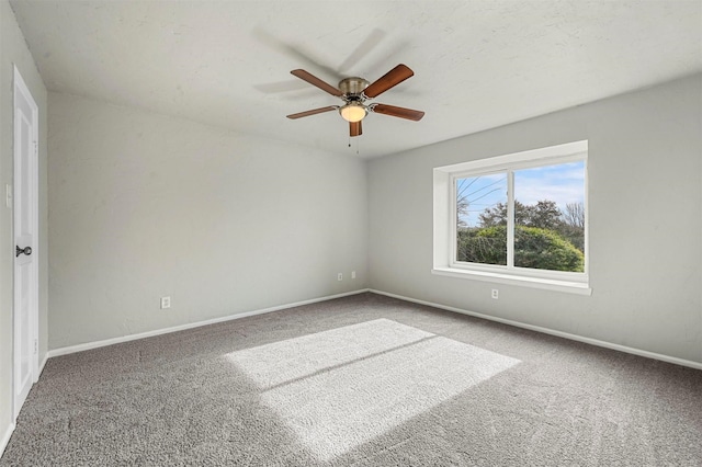 carpeted empty room with a ceiling fan and baseboards