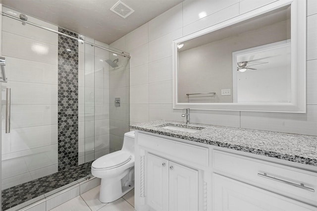 bathroom featuring toilet, visible vents, vanity, tile walls, and a stall shower