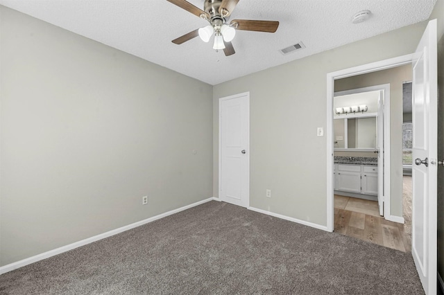 unfurnished bedroom with visible vents, a textured ceiling, baseboards, and carpet flooring