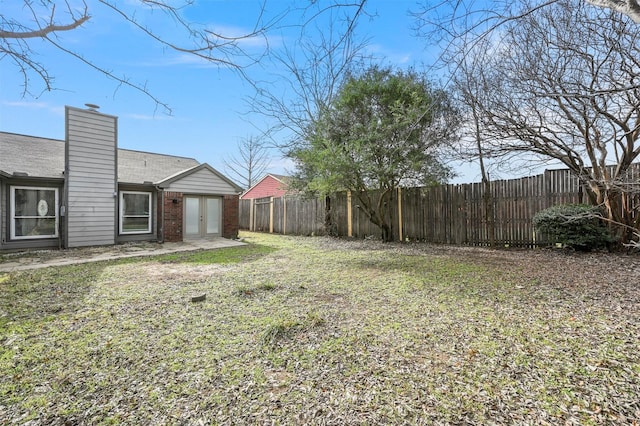 view of yard featuring a fenced backyard and french doors